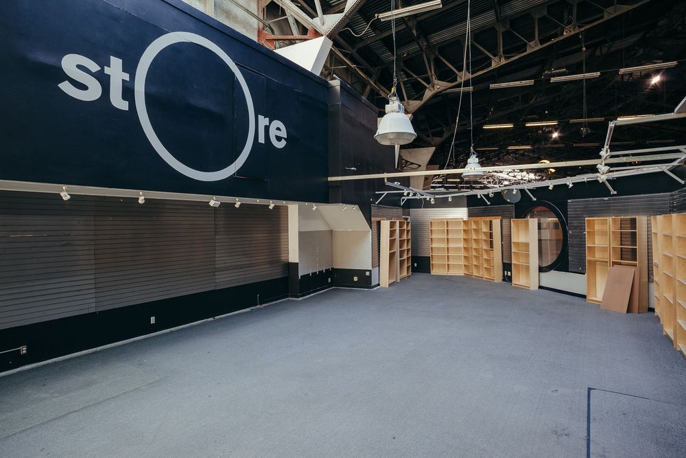 Large empty warehouse space with dark flooring and industrial ceiling features.