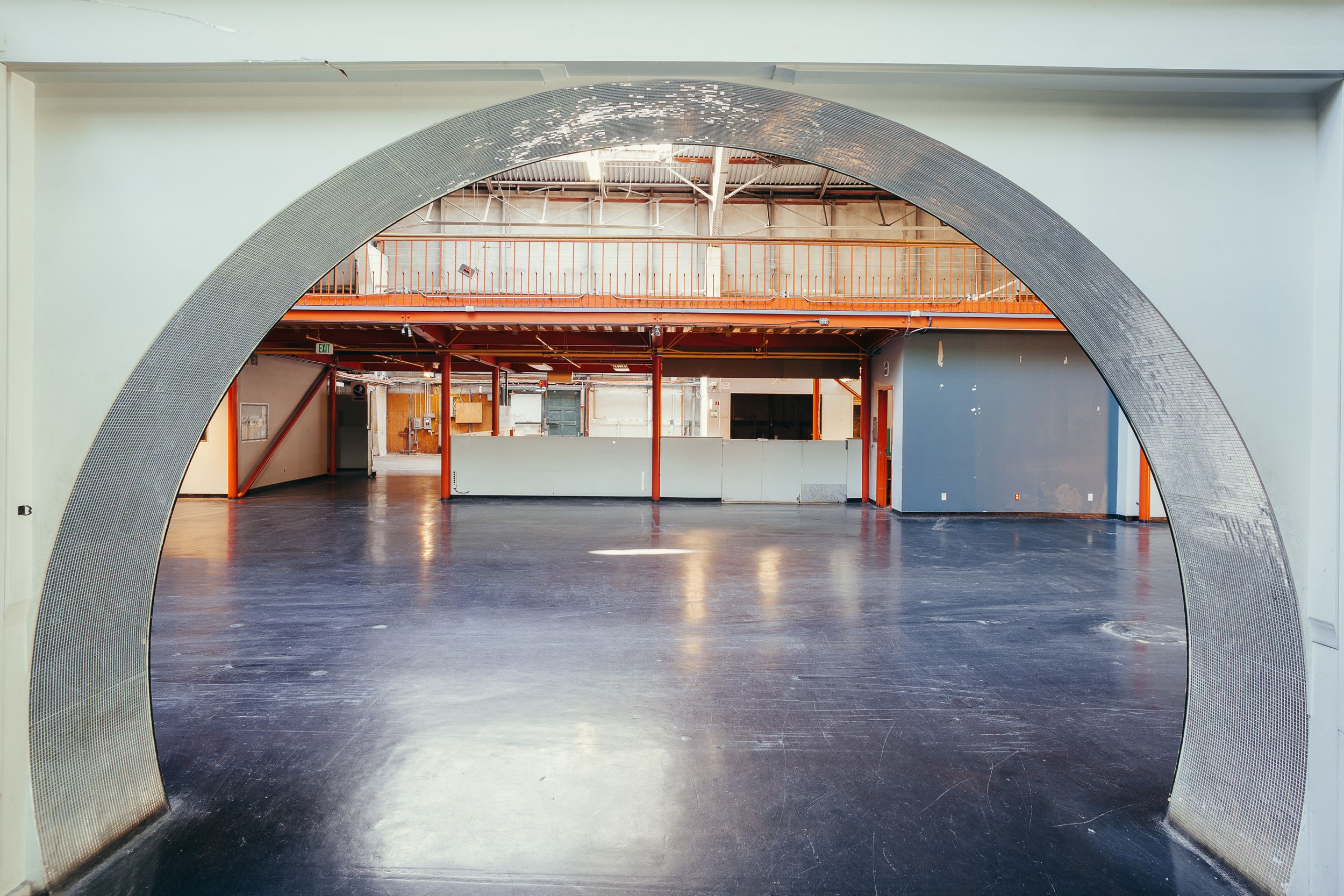 Arched entryway leading into a spacious room with polished concrete flooring.