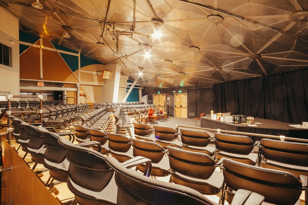 Theater-style seating arrangement with rows of brown chairs under dramatic lighting.