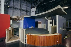 Large empty commercial warehouse space with exposed ceiling and industrial lighting fixtures.