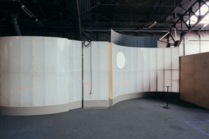 Long panoramic view of an empty warehouse interior with curved walls and high ceilings.