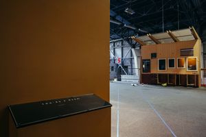Large open warehouse space with wooden structures and blue floor markings.
