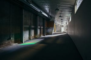 Dark corridor with dramatic lighting and industrial architectural features.