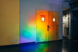 Metal doors illuminated by vibrant rainbow light effects in a dimly lit hallway.