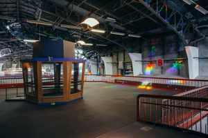 Empty indoor space with exposed ceiling, colorful railing, and central booth structure.