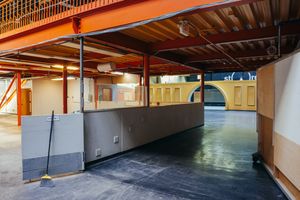 Long hallway with orange ceiling beams and grey walls leading to an arched doorway.