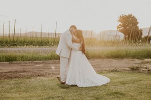A romantic sunset wedding photo of a couple embracing in a field with golden light.
