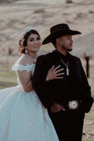 A western-themed wedding portrait with the bride in a ballgown and groom in cowboy attire.