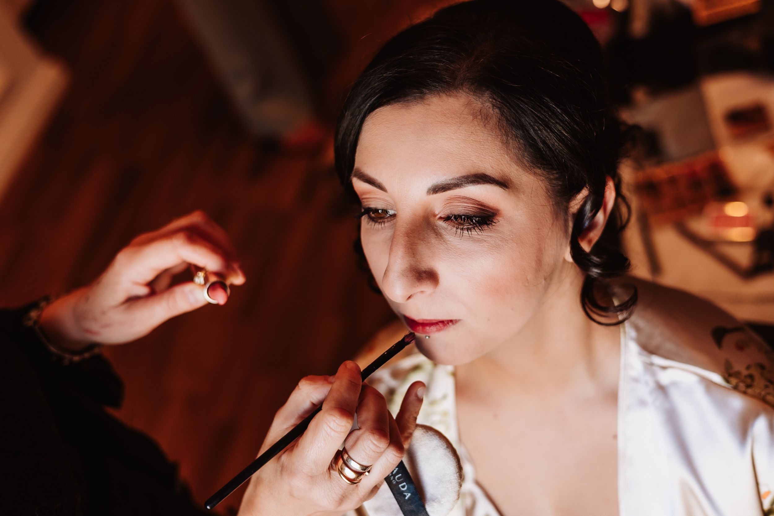 Professional makeup artist applies cosmetics to a client during a glamorous beauty preparation session.