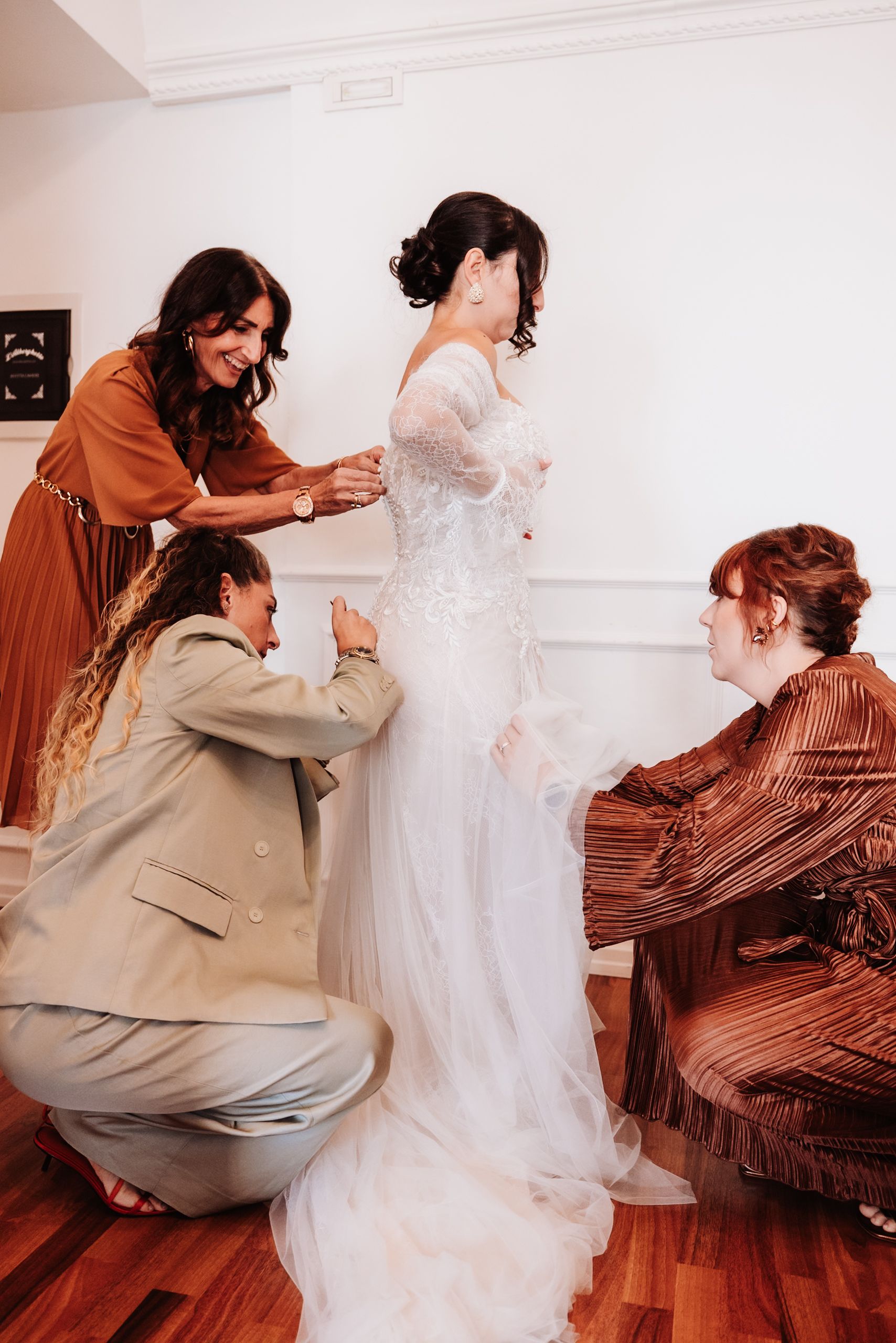 A series of images showing the process of helping someone get dressed in a white wedding gown.
