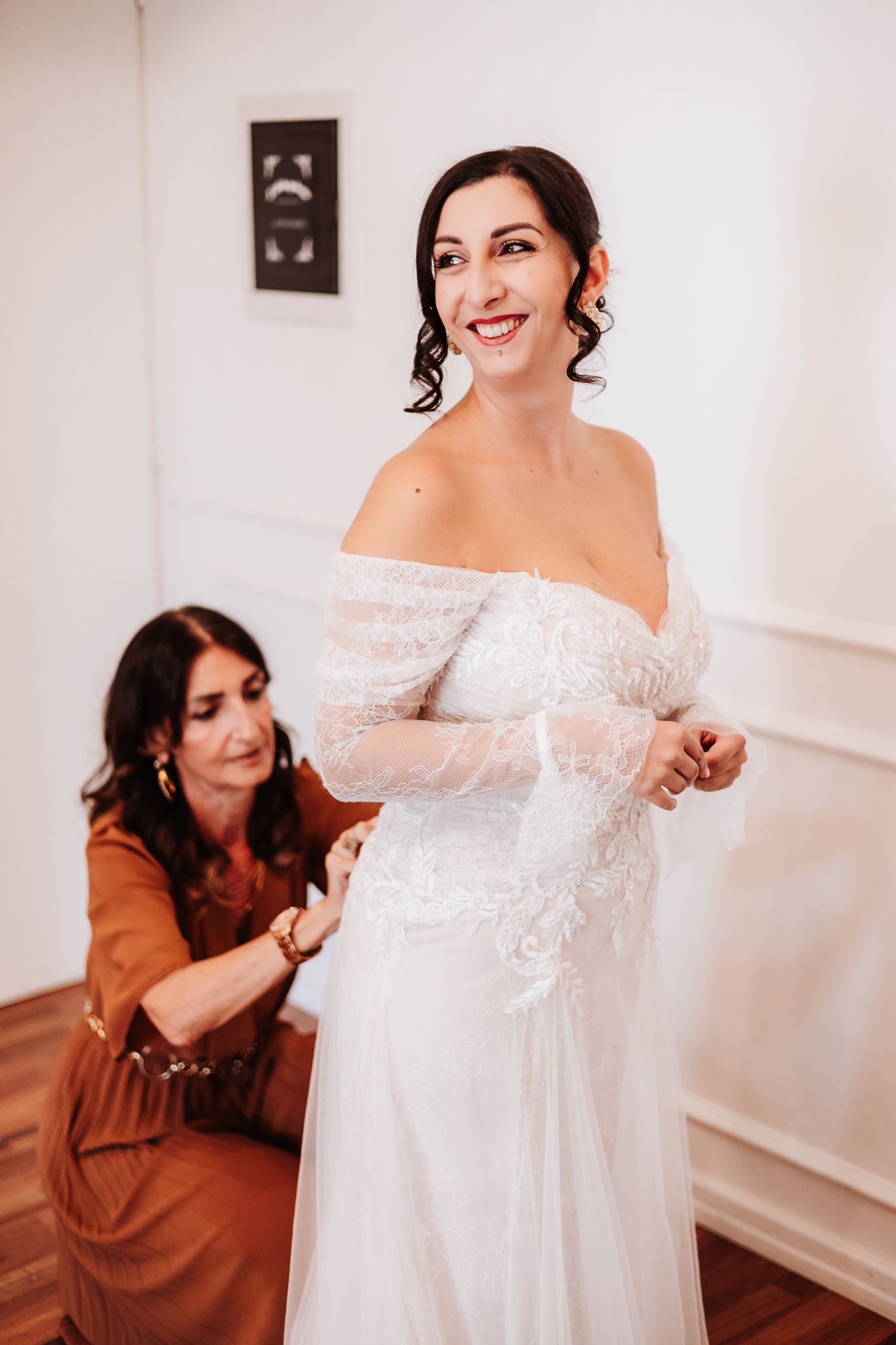 A series of four photos showing a wedding dress fitting session with an off-shoulder lace gown in a bright white room.