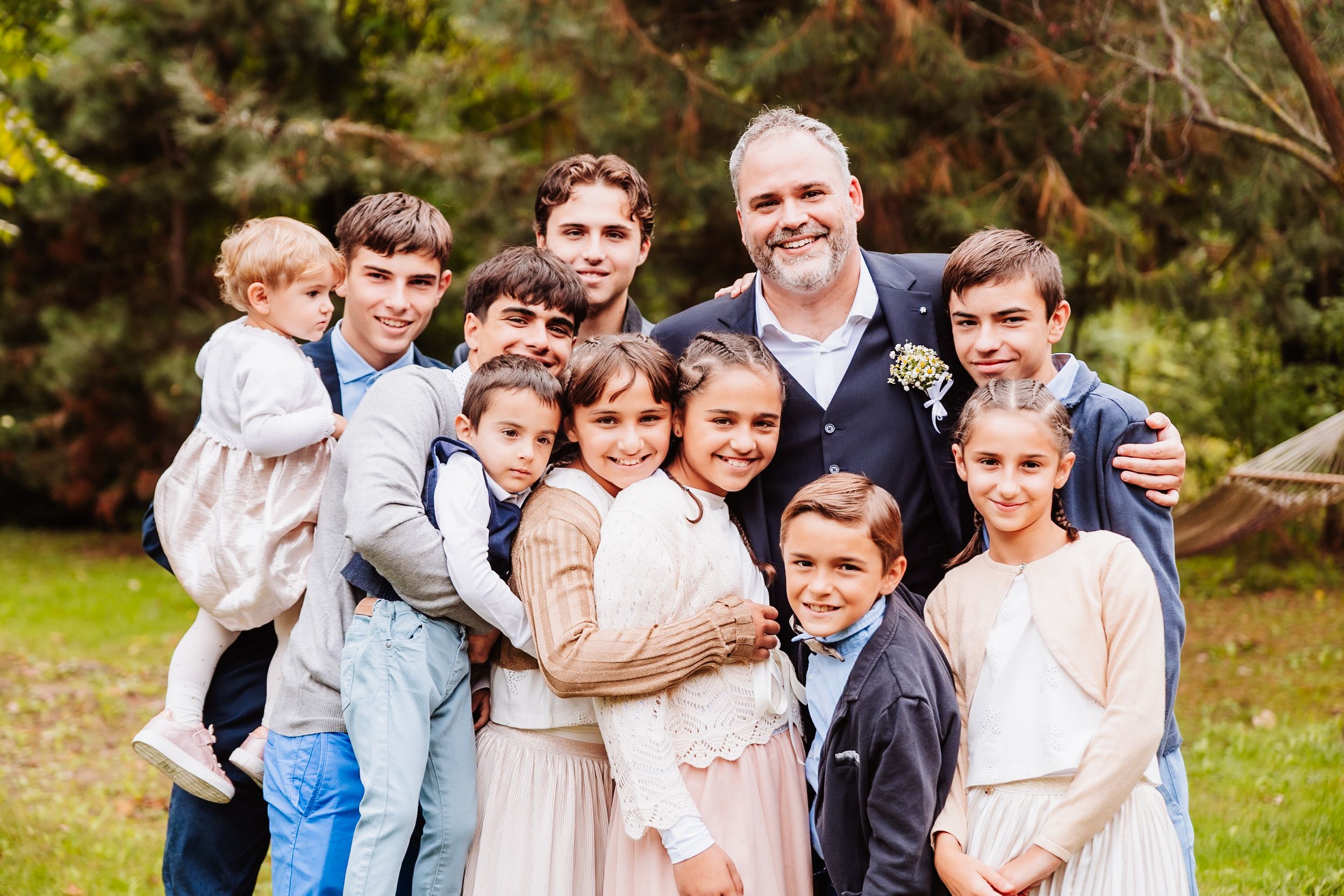 A group of people hugging and smiling together outdoors in a casual family photo session.