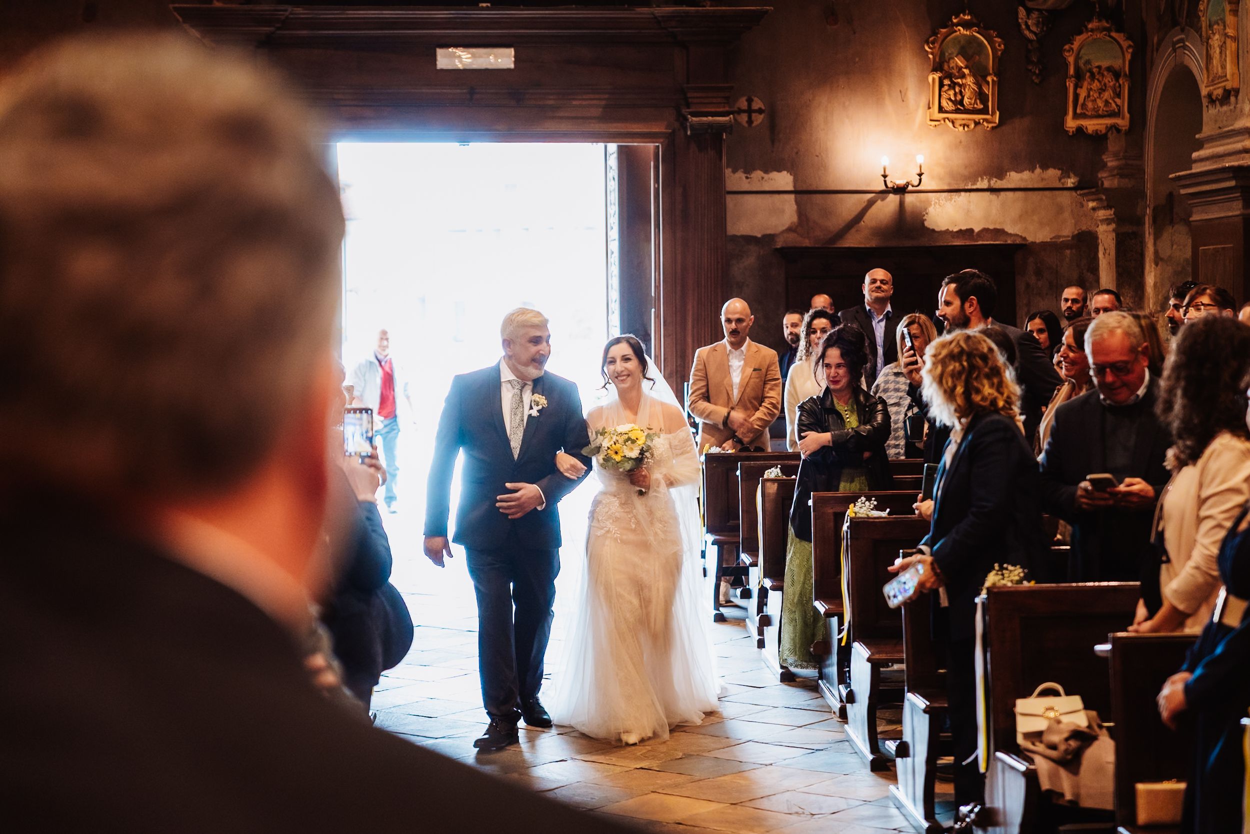 Wedding ceremony in a rustic barn venue with dark wood beams and warm lighting creating an intimate atmosphere.