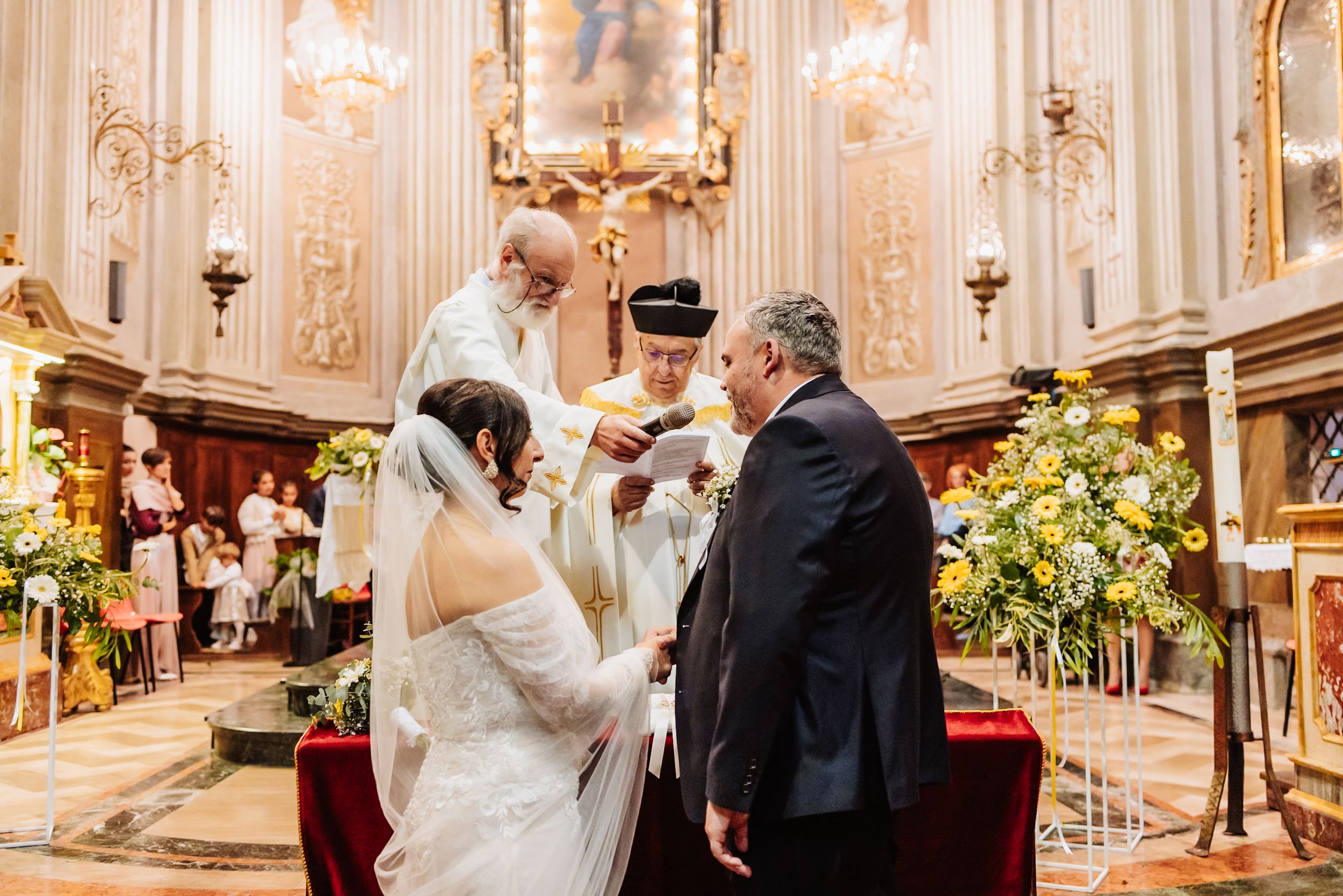A traditional Catholic wedding ceremony takes place in an ornate church with golden decorations and floral arrangements.