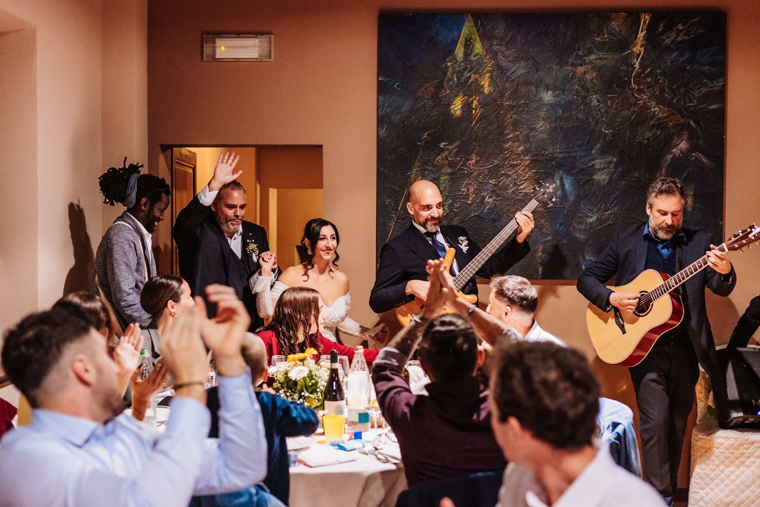 Wedding reception guests dance and celebrate on the dance floor during an indoor evening celebration.