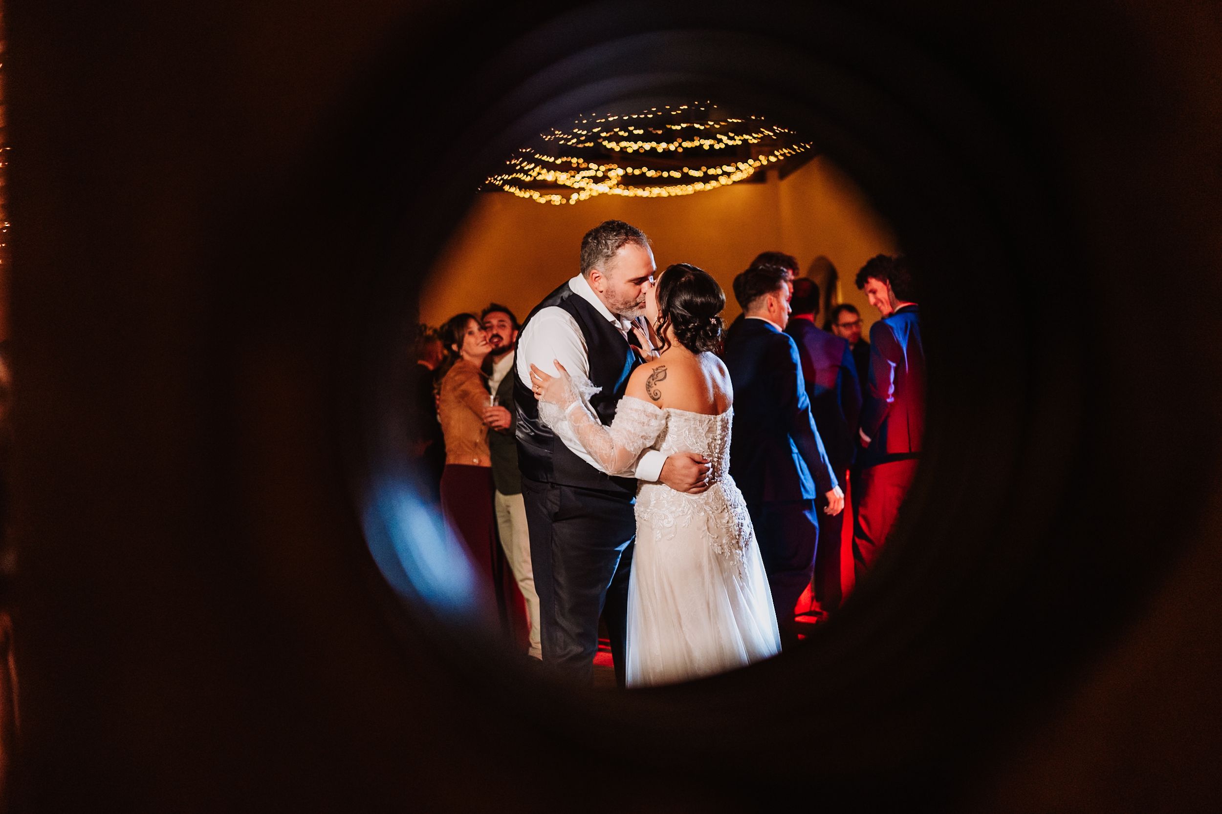 A couple shares a romantic dance together on a dimly lit dance floor at their wedding reception.