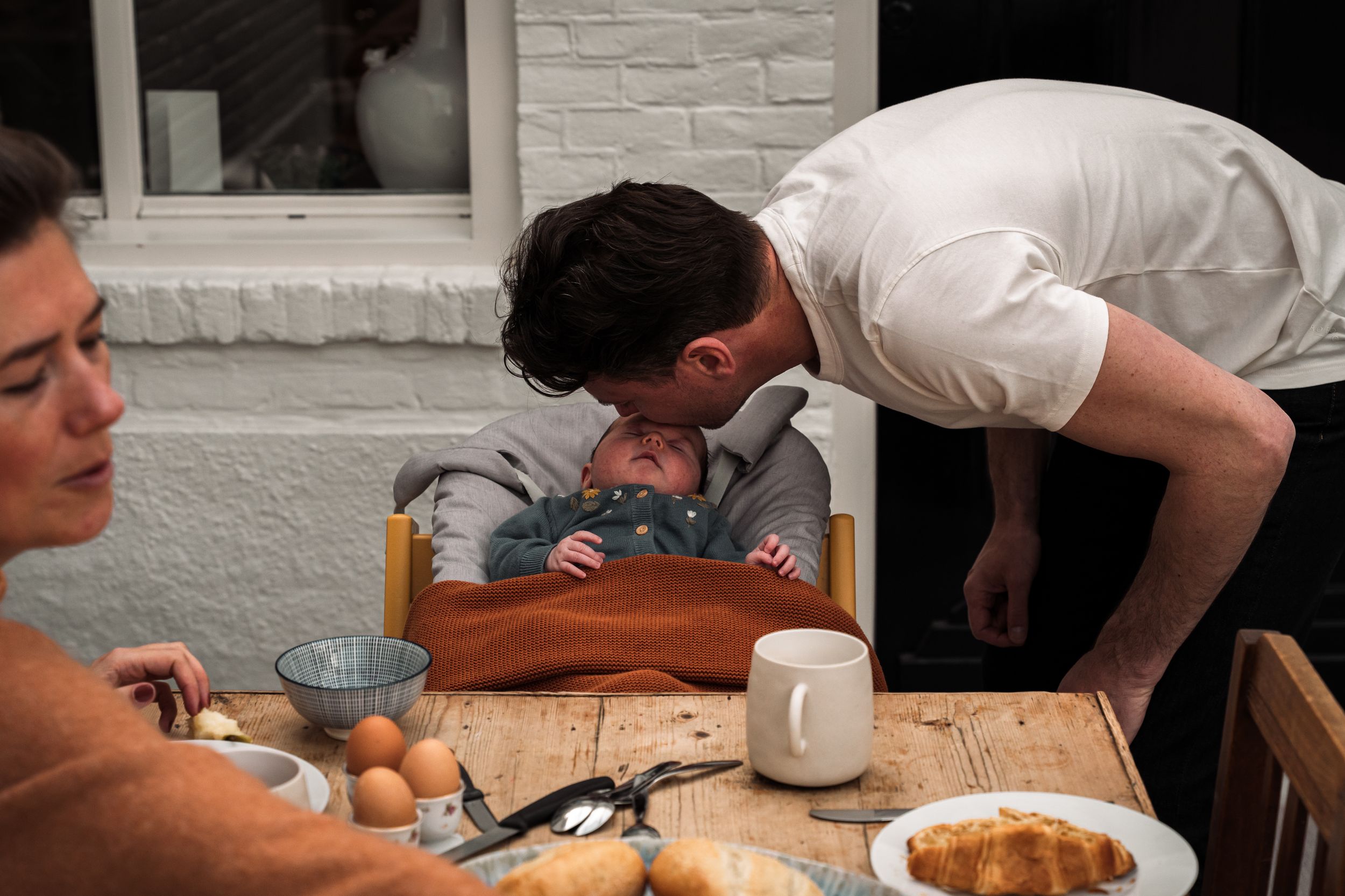 A sequence of people gathered around a table working on a cooking or baking project together.