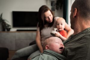 A parent holds their sleeping baby close in a tender moment at home.