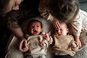 A collection of seven black and white photographs showing a newborn baby in various poses on soft blankets.