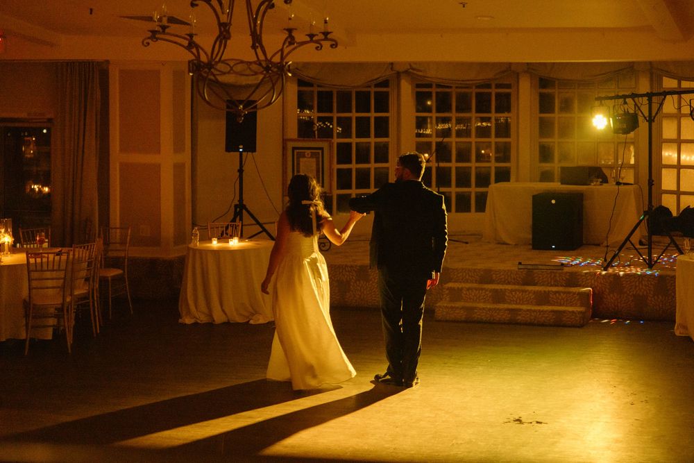 A romantic first dance between newlyweds in a warmly lit ballroom during their wedding reception.
