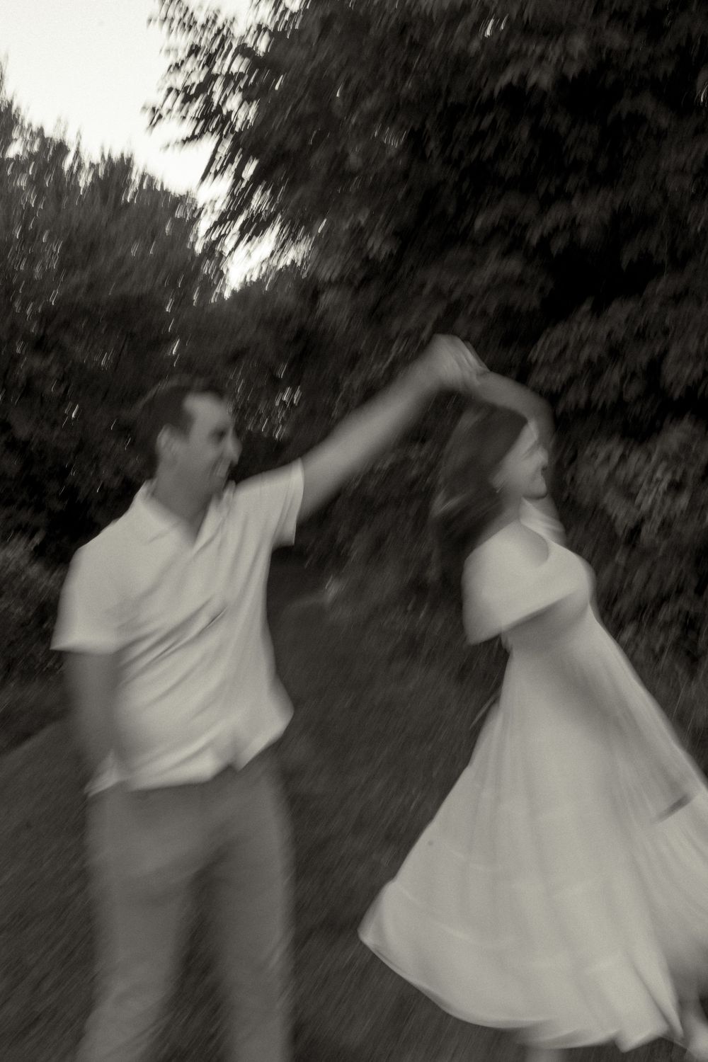 A couple dancing together outdoors in a romantic black and white photo showing movement and joy.