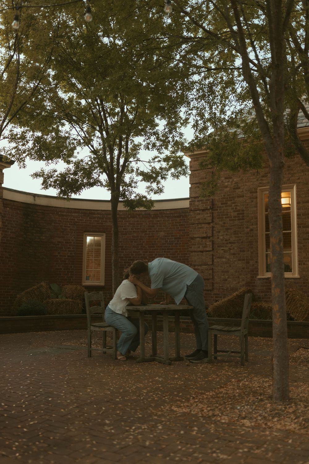 People sitting on benches near a stone wall surrounded by autumn leaves.
