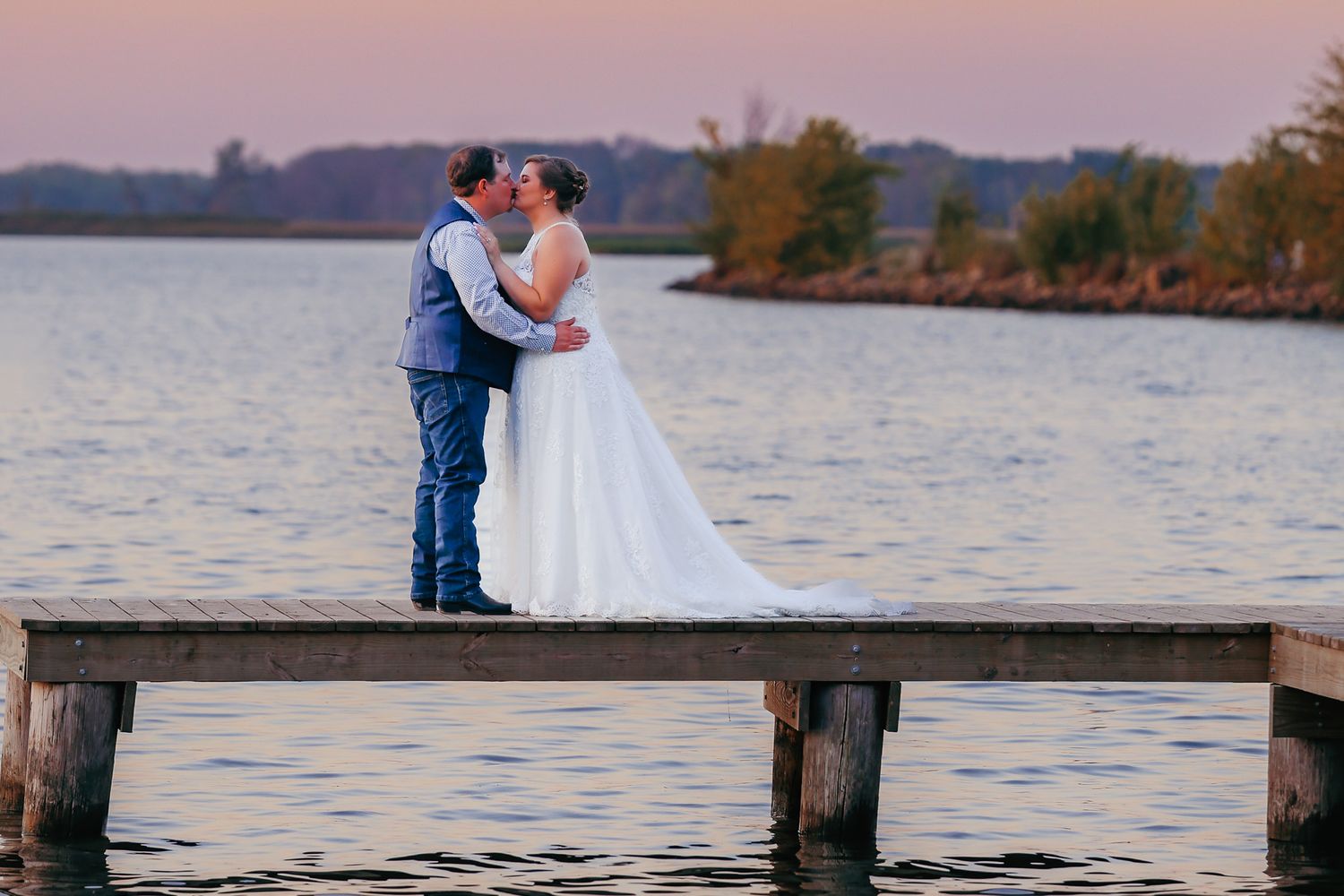 Bride and groom kissing at sunset during their wedding portraits.