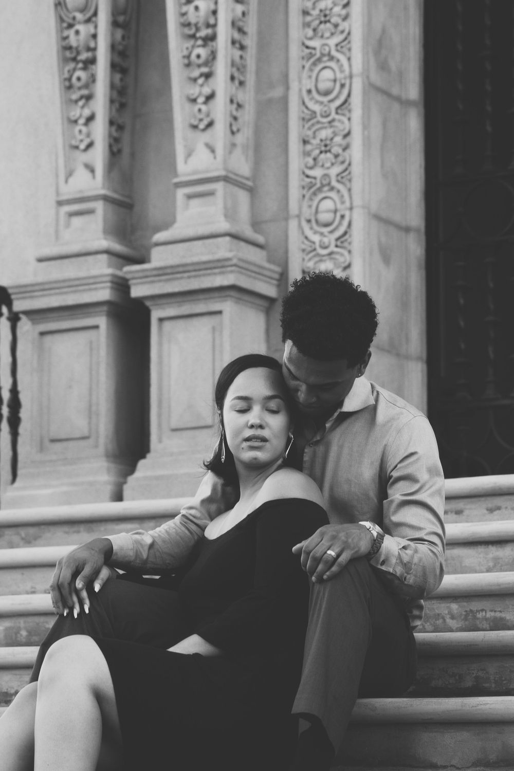 Engaged couple sitting on steps, holding one another