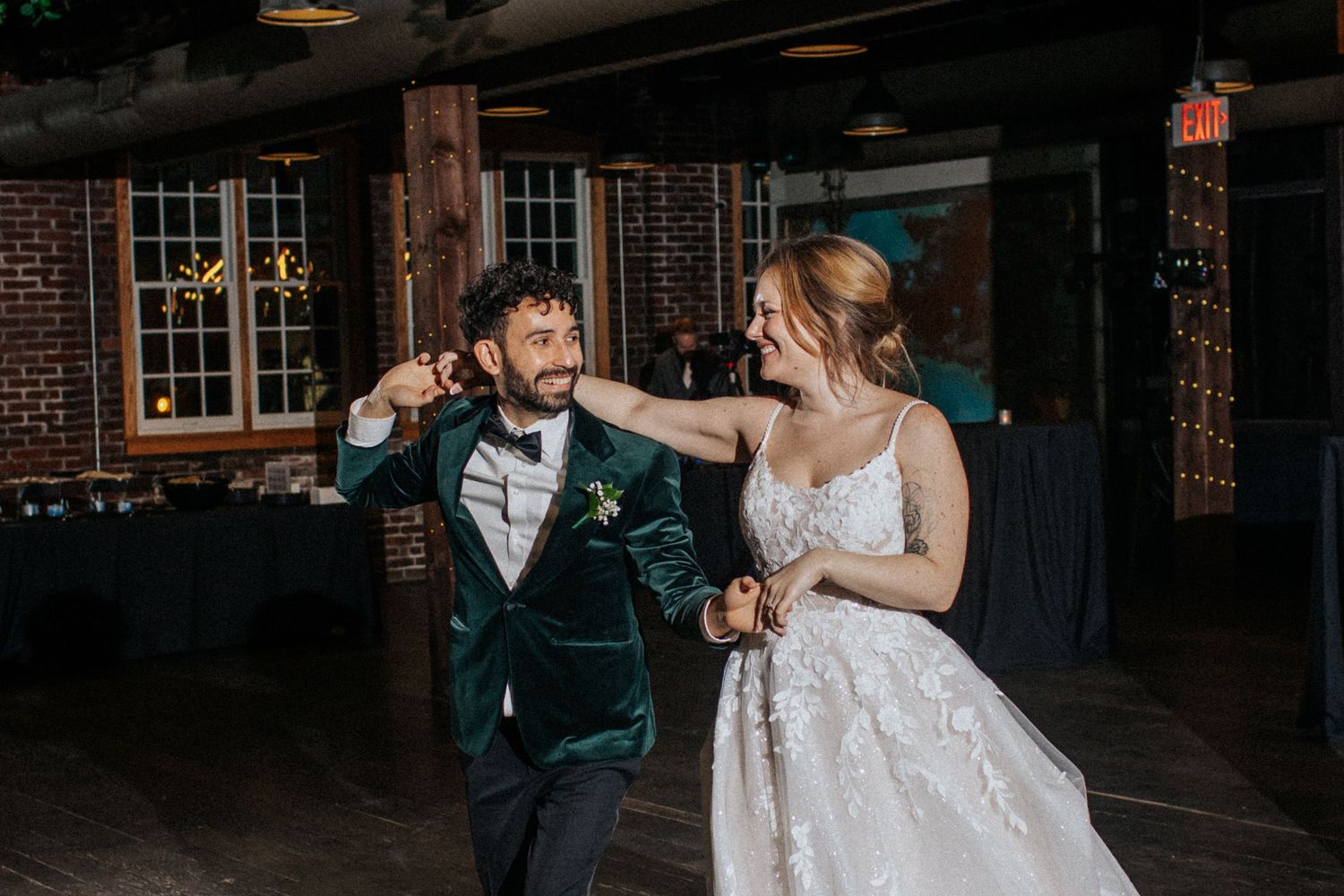Couple sharing an intimate moment during their wedding reception in a rustic brick-walled venue.
