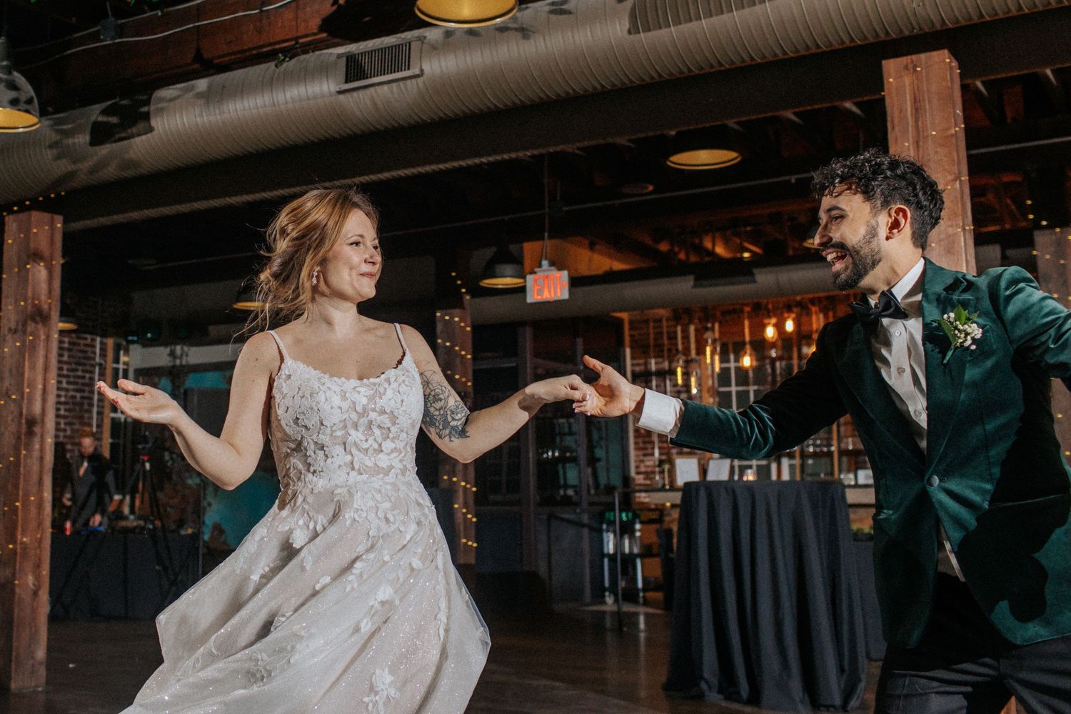 Couple sharing a romantic dance moment in a rustic venue with wooden beams and green wall accents.