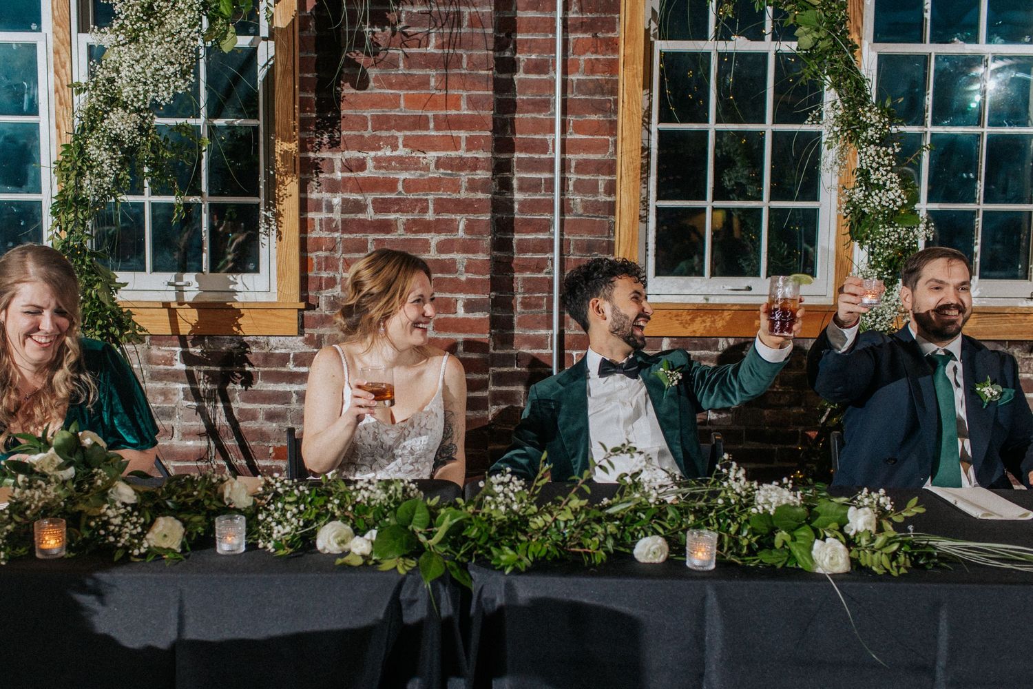 Wedding venue decorated with greenery and flowers against exposed brick walls and large windows.