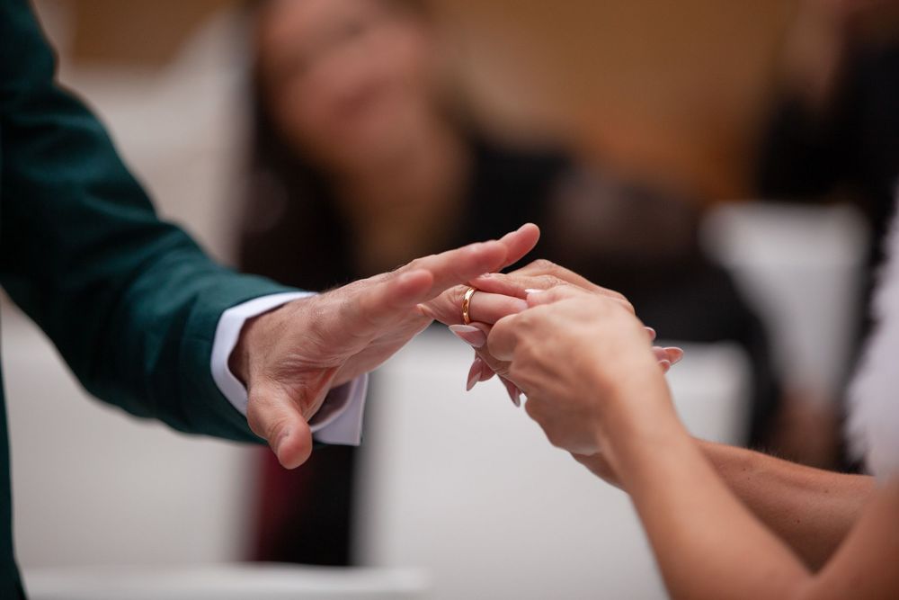 Groom placing a wedding ring on brides finger during a wedding ceremony.