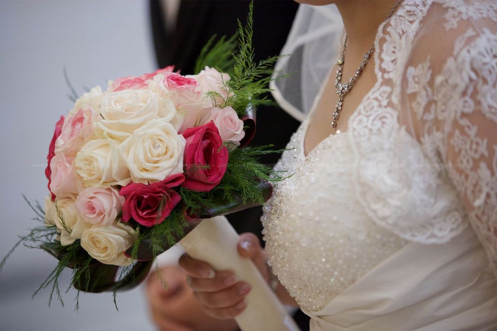 A bridal bouquet featuring pink and white roses with delicate lace details on a wedding dress.