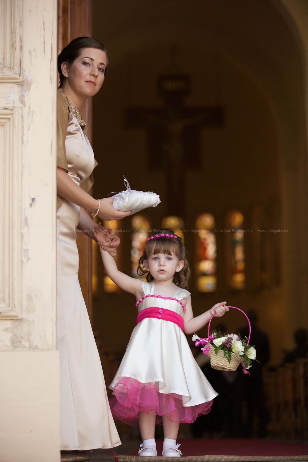 Young flower girl in white dress twirls in an elegant hallway.