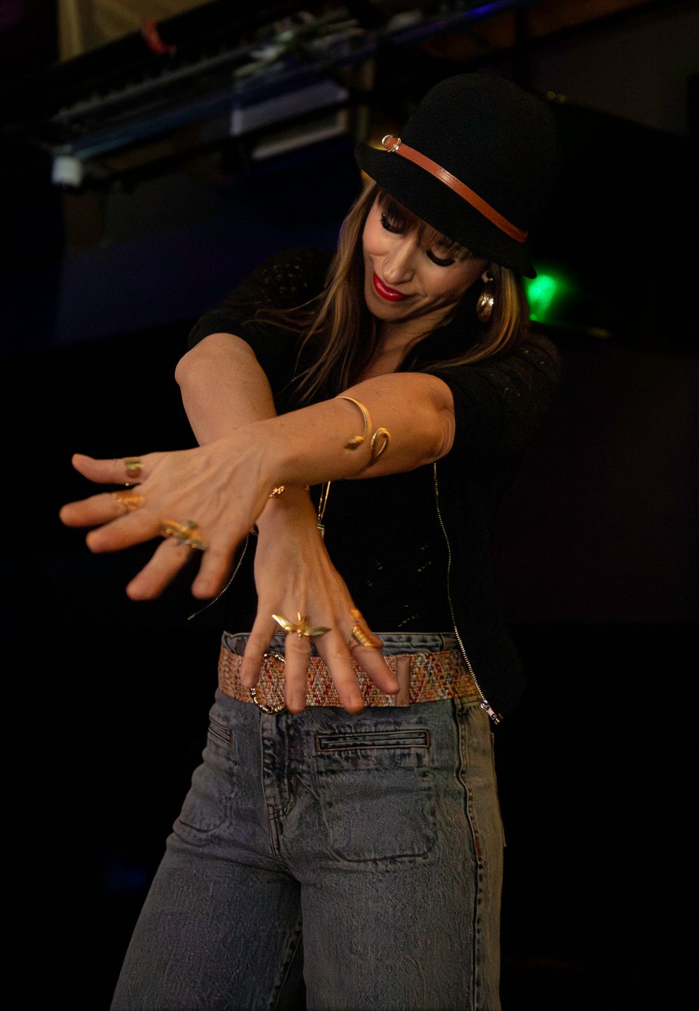 Person in jeans showing off their hands in a sequence of artistic dance movements against a dark background.