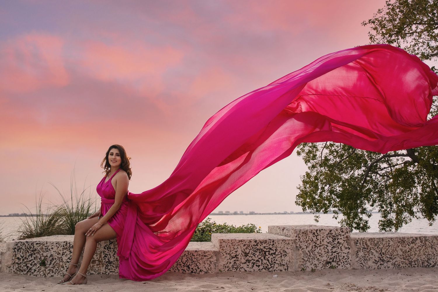 A flowing pink dress billows dramatically against a sunset sky creating an ethereal silhouette effect. Flying dress photos