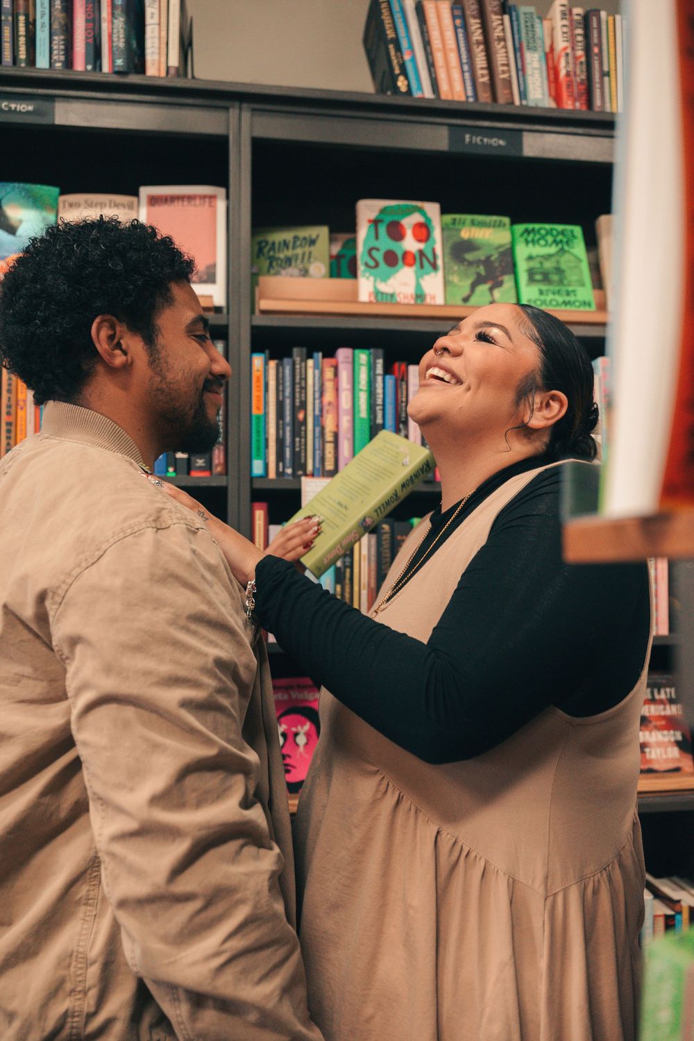 A playful moment captured between two people laughing together in a library setting.
