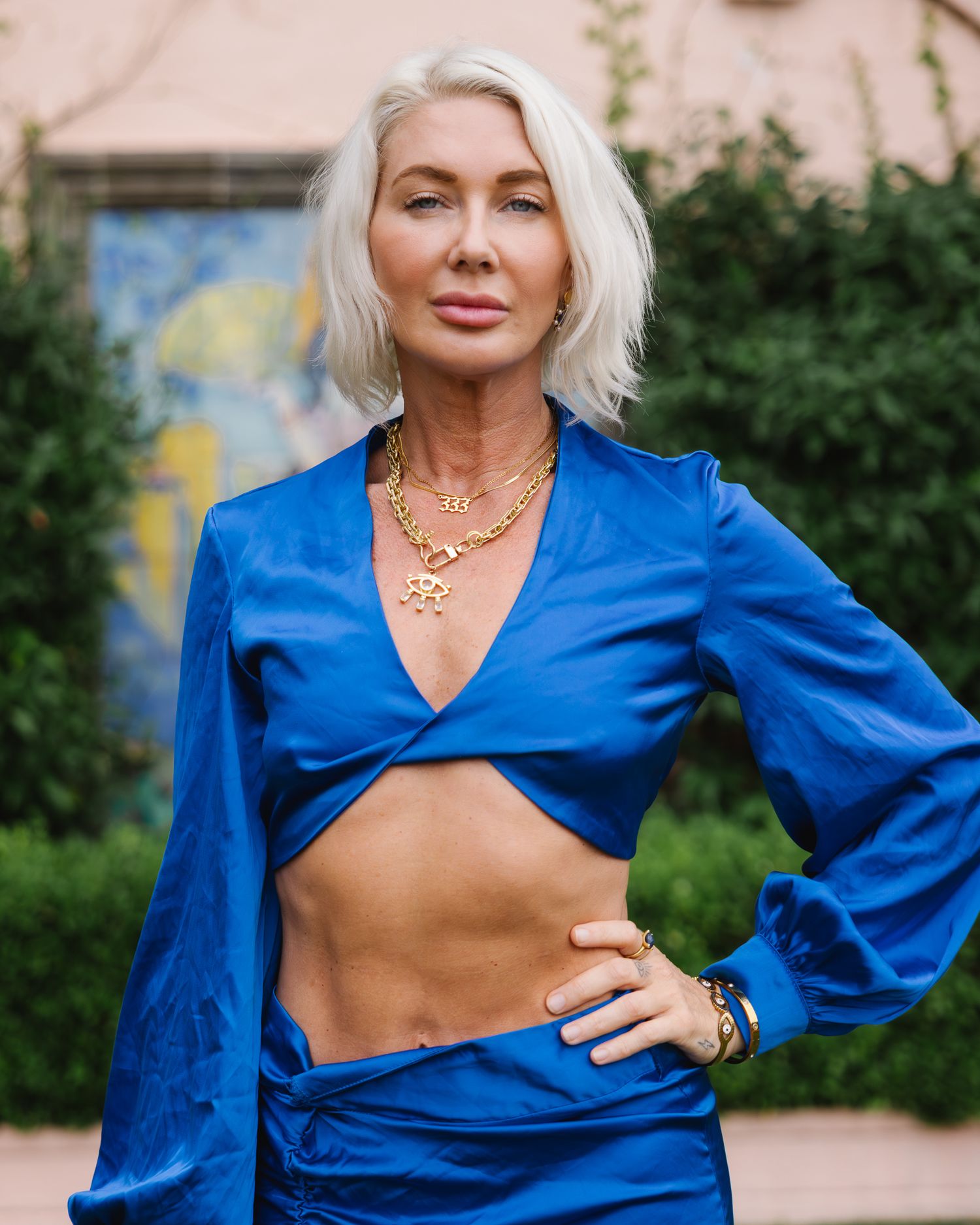 A woman in a vibrant blue wrap top poses outdoors against a natural backdrop.