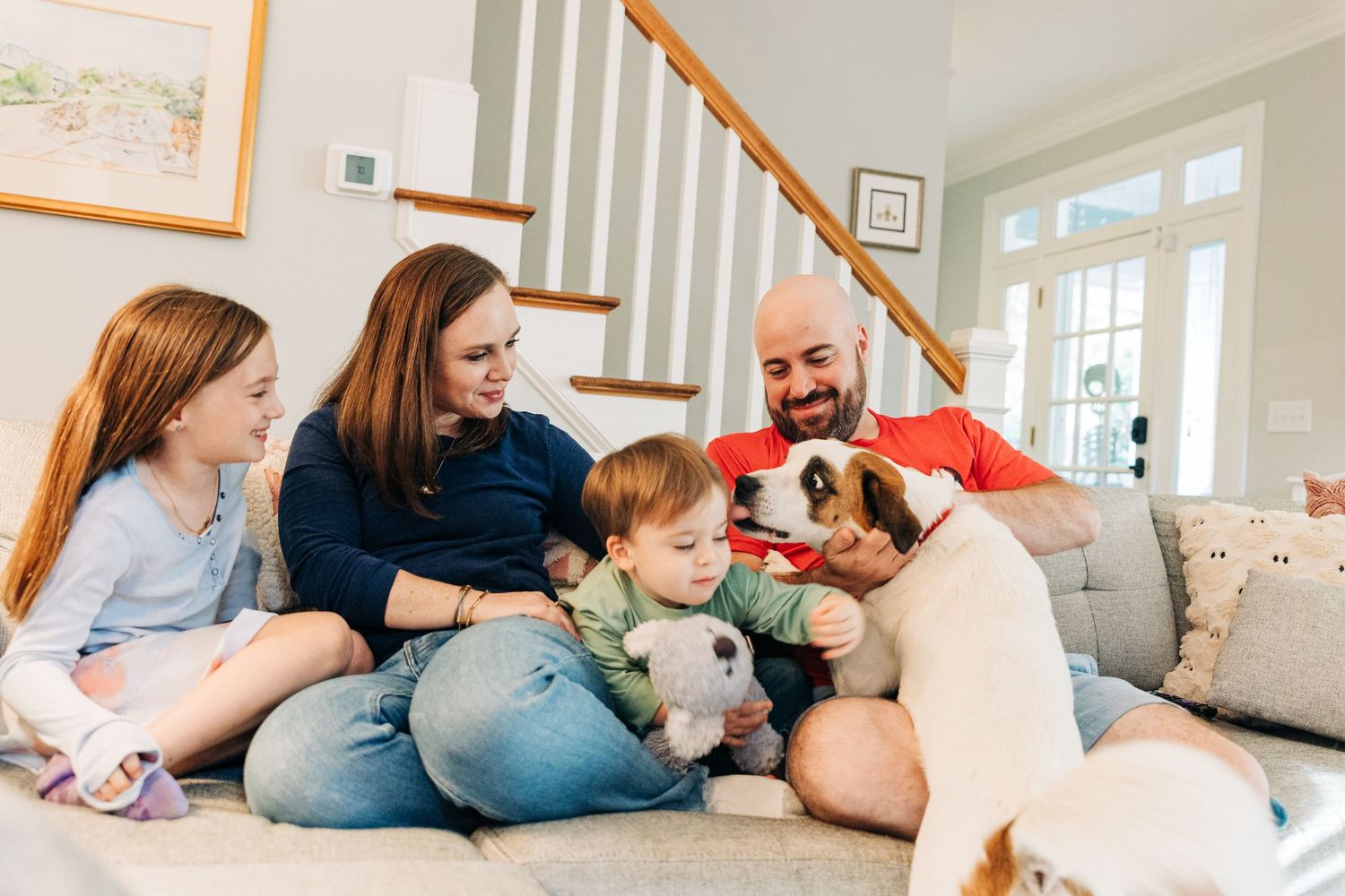 A family sitting together on the couch with their dog for Charlotte family photos.