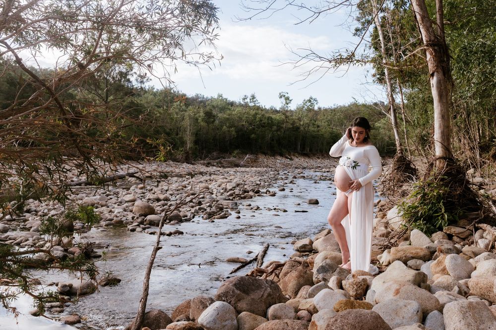 Rocky riverbank with natural boulders and trees creating a serene outdoor setting.