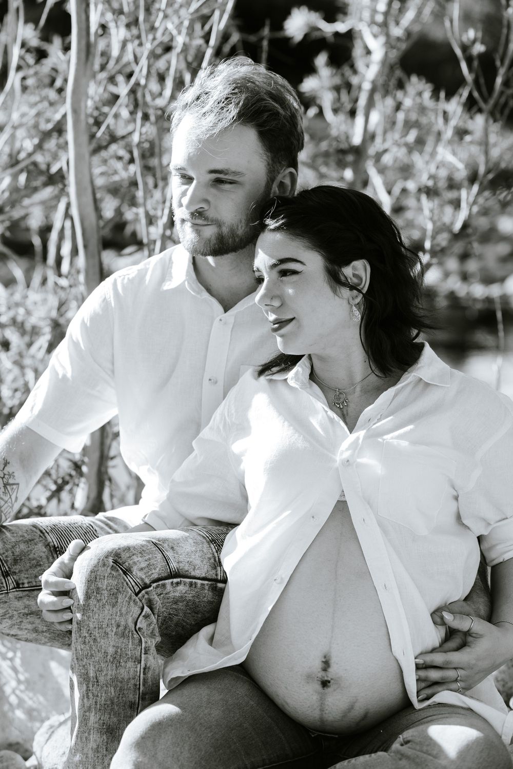 A romantic black and white photo series showing a couple in white clothing embracing on a rustic wooden bench.