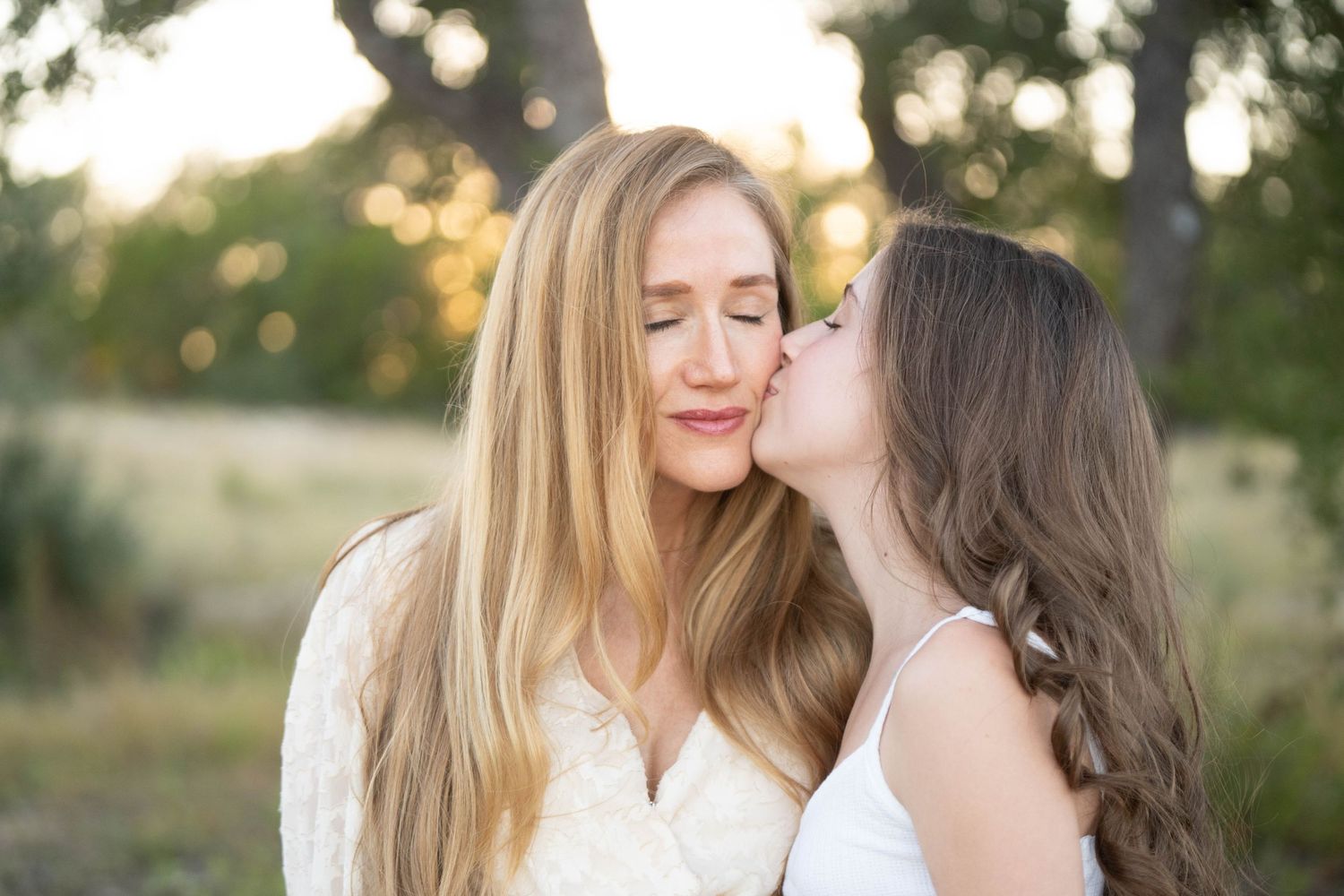 A couple shares an intimate moment together outdoors during golden hour in a natural setting.