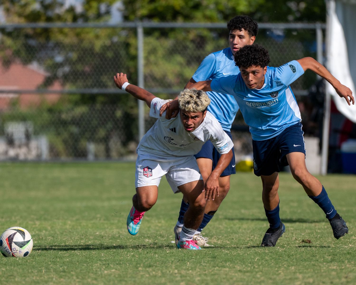 Soccer players battle for possession of ball during competitive match.