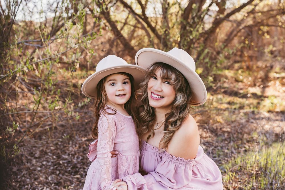 Family wearing coordinated pink outfits poses together in a natural outdoor setting.