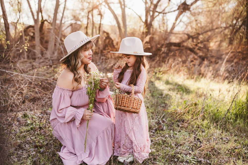 Multiple shots of people in pink dresses sitting in a sunlit meadow with wicker baskets.