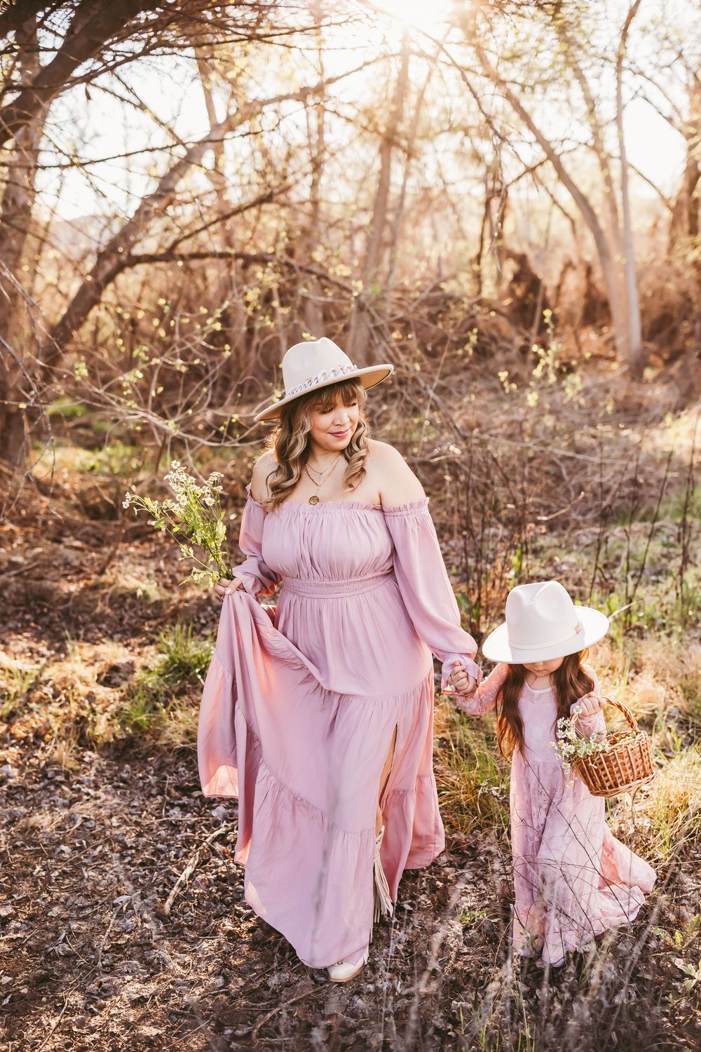 Ethereal scene with flowing pink dresses and sun-drenched woodland setting during golden hour.