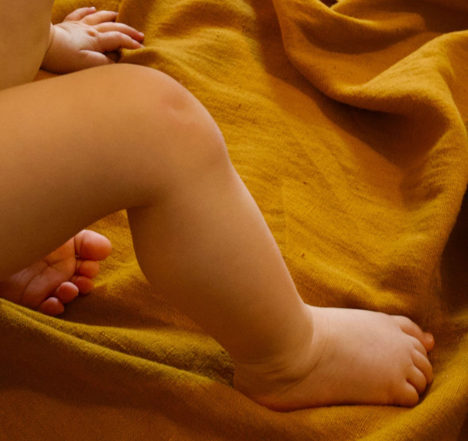 Petits pieds de bébé sur un tissu chaleureux lors d’une séance photo bébé lifestyle par WA Visuel photographe famille en Provence.