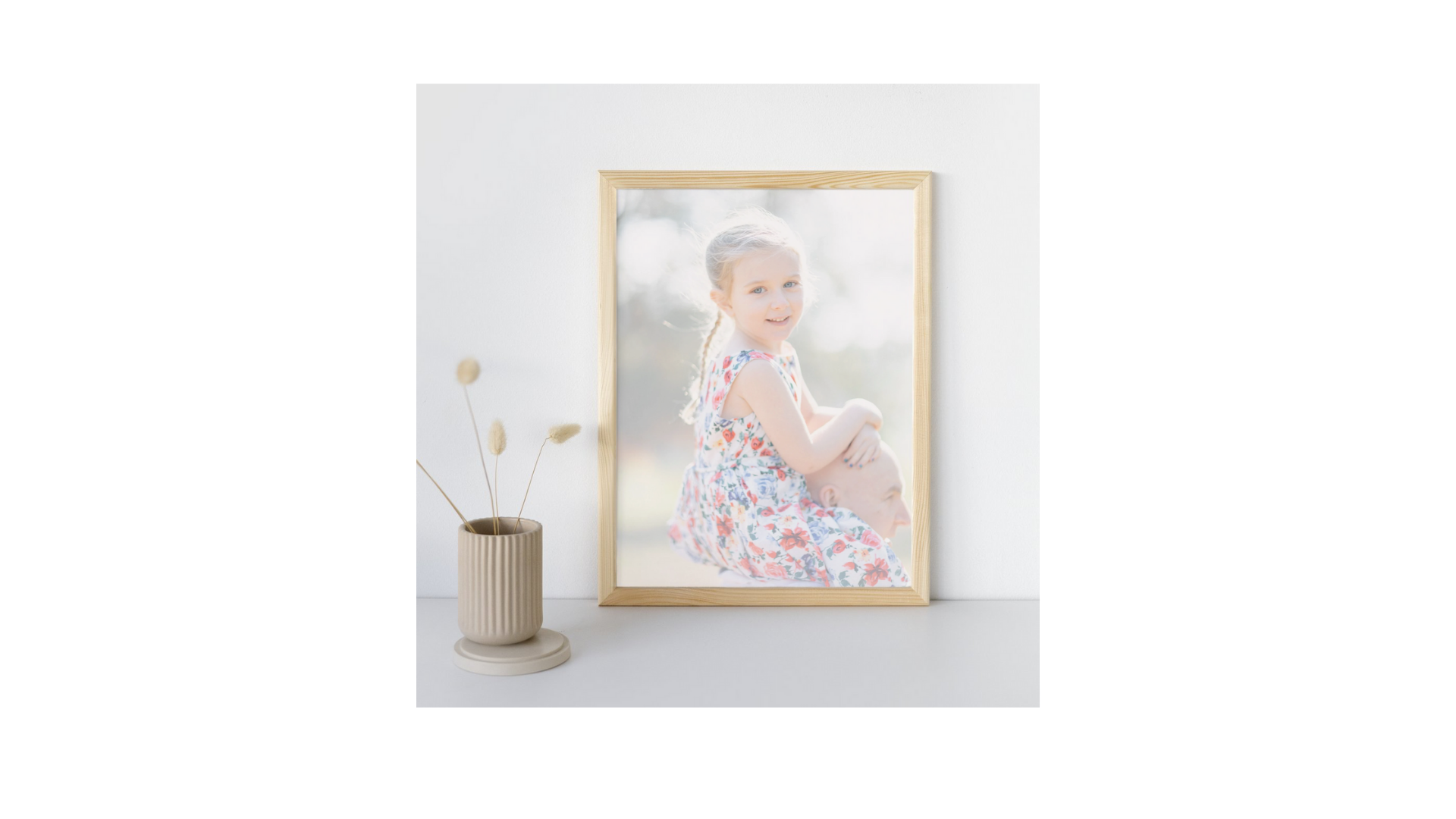 A framed portrait in a gold frame displayed on a white wall with minimalist decor.