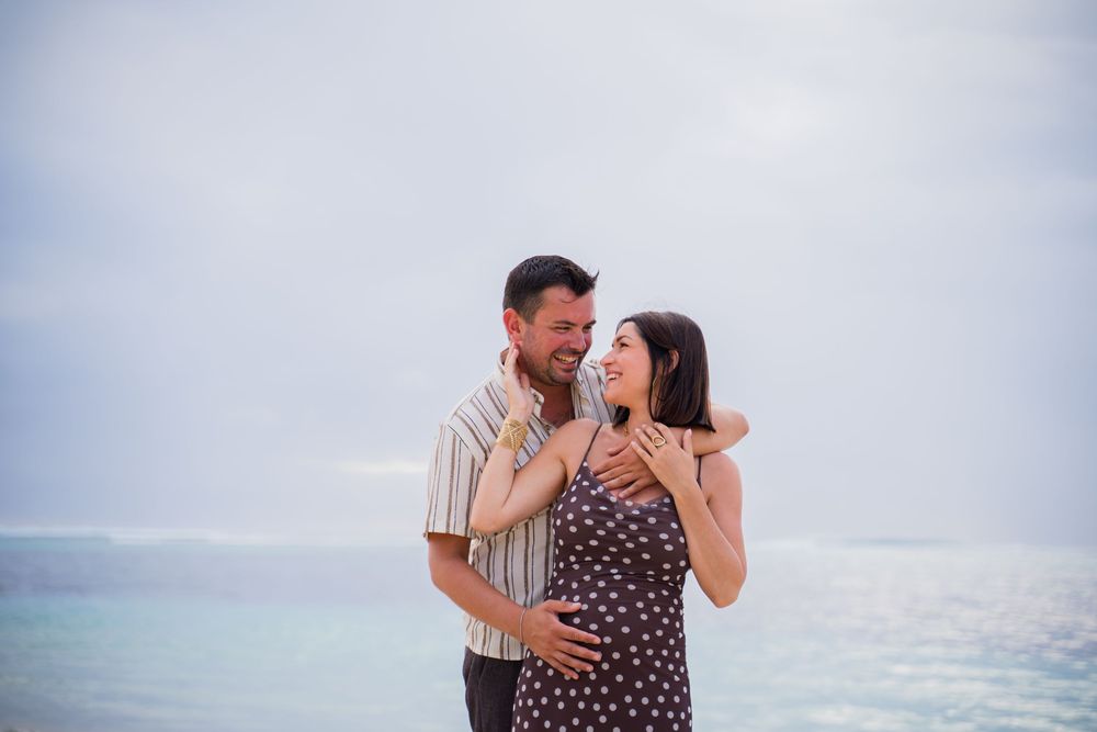 A couple shares an intimate moment while standing in the ocean waves.