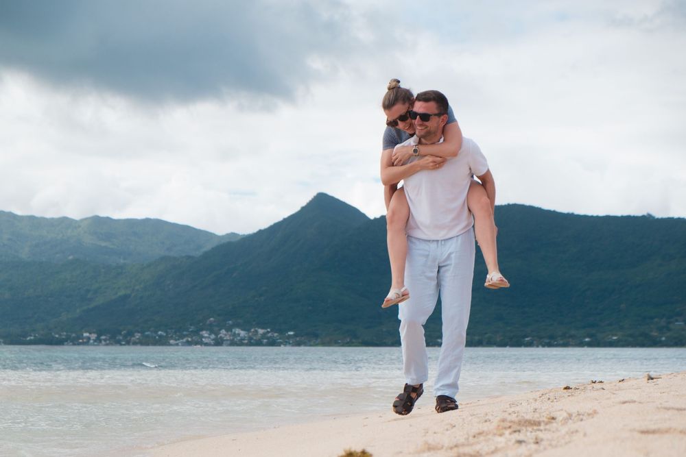Romantic beach photoshoot with mountains and calm waters in the distance.